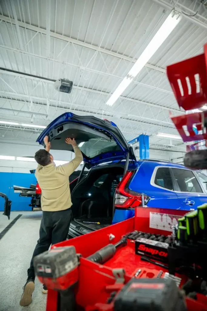 Technician performing frame straightening on blue vehicle in EZ Tech collision repair shop.