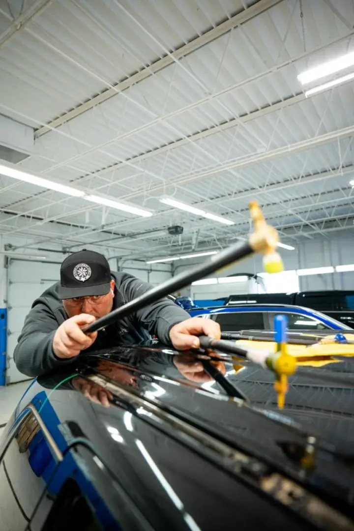 EZ Tech technician performing paintless dent repair on a blue vehicle.