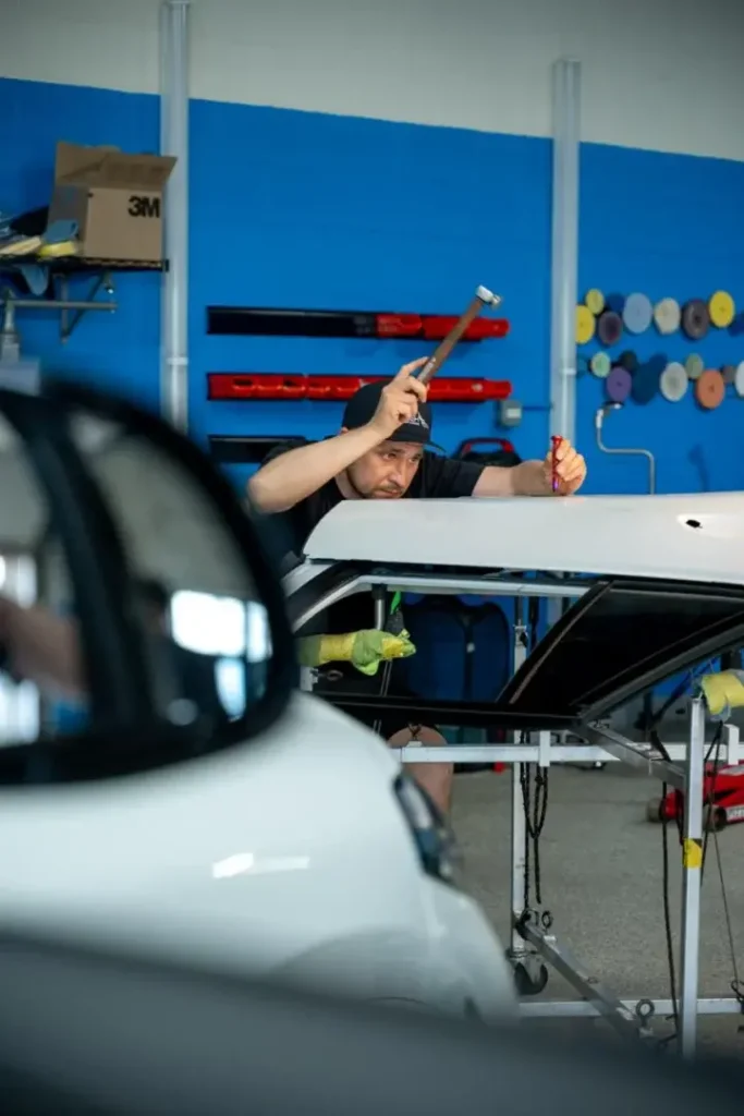 EZ Tech technician performing frame straightening on white vehicle with specialized tools.