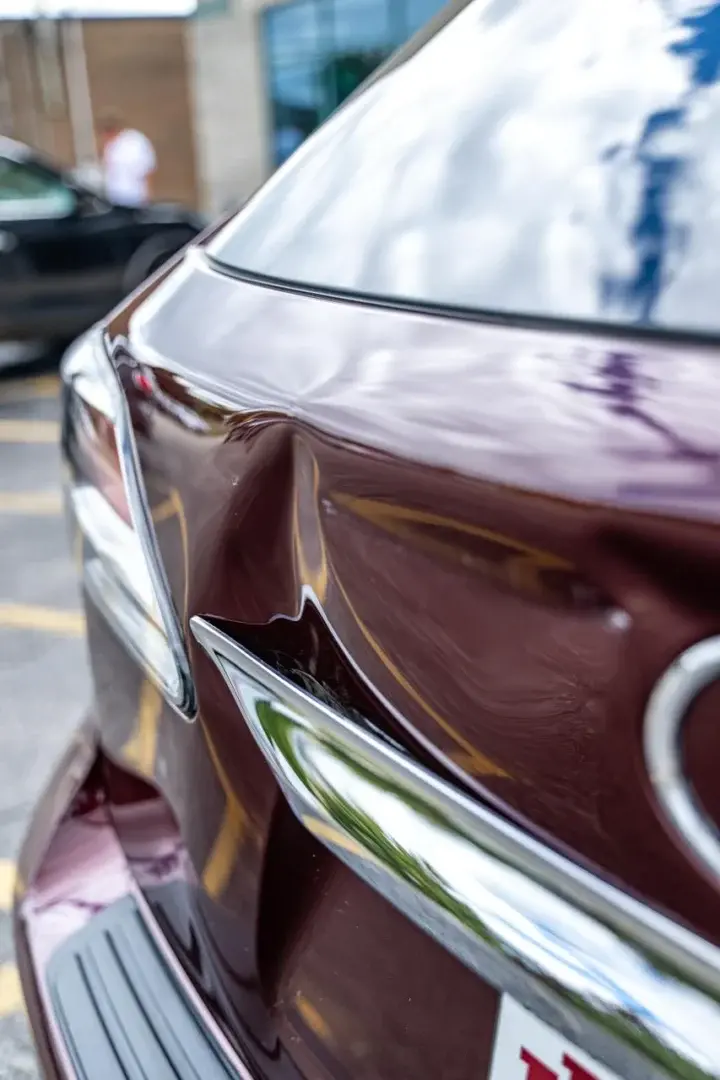 Dented car trunk corner illustrating paintless dent repair process