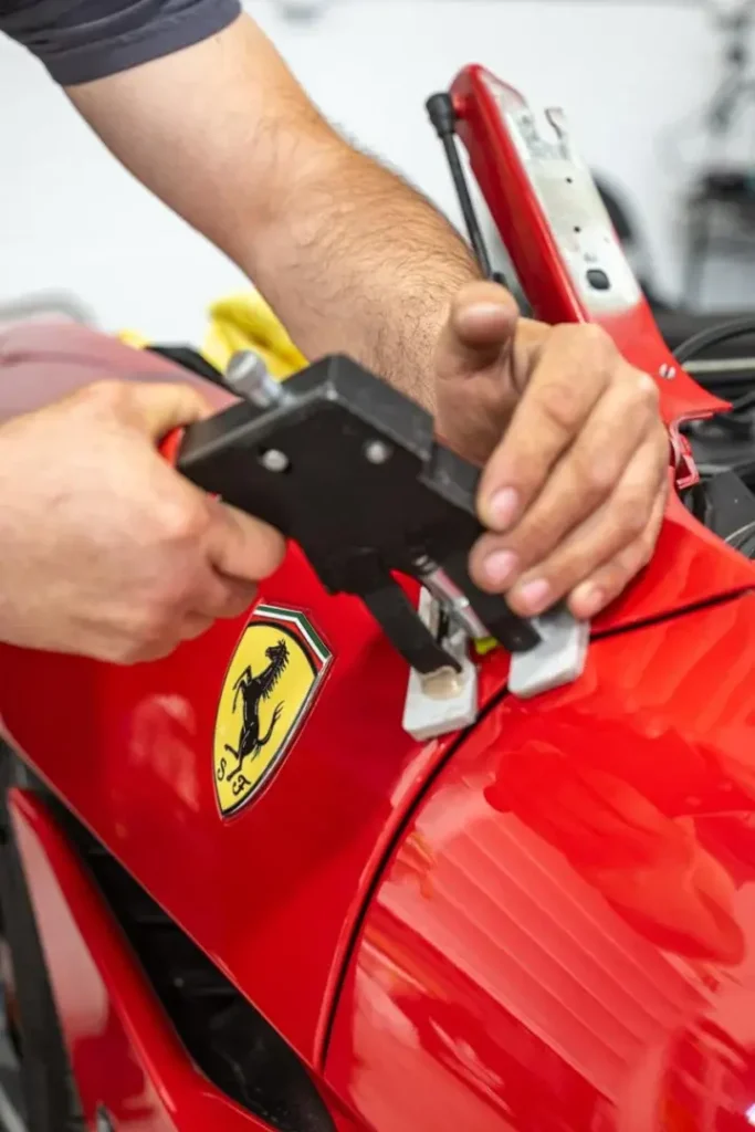 EZ Tech PDR technician repairing Ferrari hood dent, collision repair services.