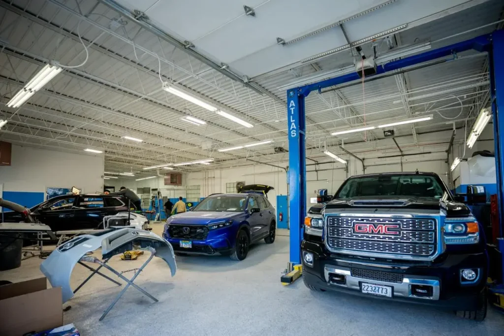 Vehicle on lift in Ez Tech collision repair shop, body panel replacement specialists.